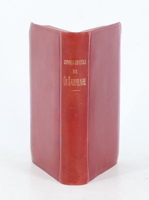 an old red book sitting on top of a table next to a white wall