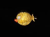 a gold fish with a red bead on it