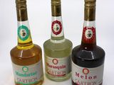 three bottles of liquor sitting next to each other on a white surface