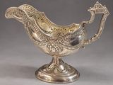 a silver plated sauce boat with a bird on the handle