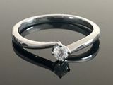 a silver ring with a diamond on it on a table