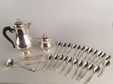 a lot of silver spoons and a silver teapot on a table