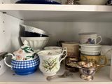 many cups and bowls on a shelf in the kitchen