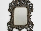an antique mirror with a decorative frame on a white wall