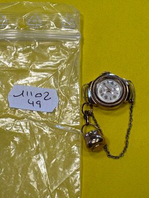 une montre de poche et une chaîne posées sur une table jaune