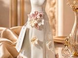 une figurine représentant une robe de mariée posée sur une table, à côté d'un vase de fleurs