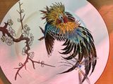une assiette colorée ornée d'un oiseau, posée sur une table