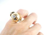a person ' s hand holding a gold and diamond ring