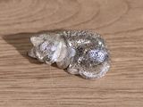 a silver figurine of a cat on a wooden table