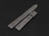une paire de bracelets de montre en cuir gris posés sur une surface noire
