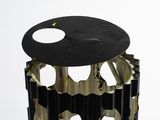 a metal trash can with holes in it on a white surface