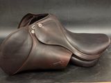 brown leather horse saddles on a black surface with a wooden stick