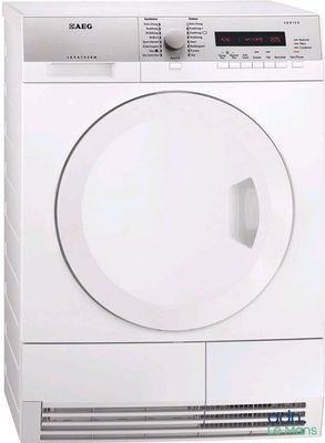 un sèche-linge blanc posé sur un autre sèche-linge, à côté d'un troisième sèche-linge