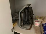 a hose on a shelf in a cabinet with a roll of tape on it