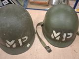 pair of army green helmets with white letters on them sitting on a table