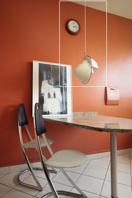 une table et des chaises dans une pièce où est accrochée une horloge au mur