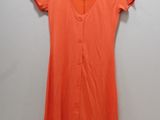 an orange dress hanging on a hanger against a white wall