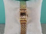 une photo d'une montre-bracelet en or posée sur un oreiller