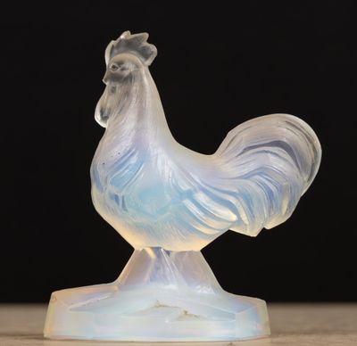 une figurine en verre représentant un coq, posée sur une table