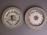 two plates with a coat of arms on them sitting on a table