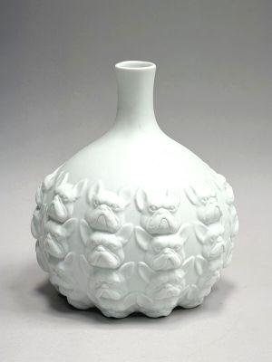 a white vase with flowers on it sitting on a table