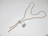 collier orné de perles blanches et d'une étiquette, posé sur un fond blanc