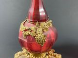 a red glass vase with a gold decoration on it