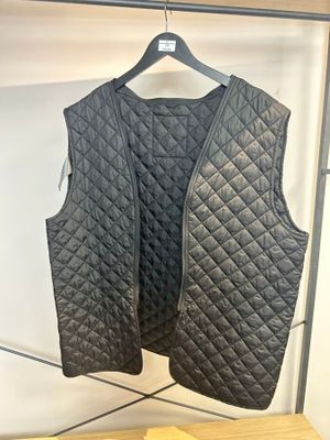 un gilet matelassé noir suspendu à un portant dans un magasin de vêtements