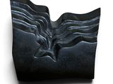 une sculpture noire représentant un visage sur une surface blanche