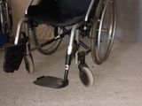 un fauteuil roulant qui se trouve dans une pièce, à côté d'une chaise