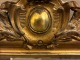 a mirror with a gold frame and a gold clock on it