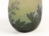 a green vase with leaves on it on a white surface