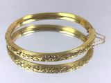 un gros plan sur deux bracelets en or posés sur une surface blanche
