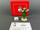 a toy figure of a man in a green uniform with a red box in the background