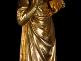a gold statue of a woman holding a book