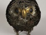 un hibou réalisé à partir de pièces métalliques posées sur une surface blanche