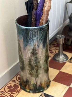un vase contenant des parapluies, posé sur un sol carrelé