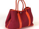 un sac à main orange et rouge posé sur une surface blanche