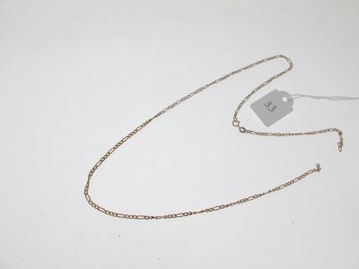une chaîne en or à laquelle est accrochée une médaille, posée sur une surface blanche