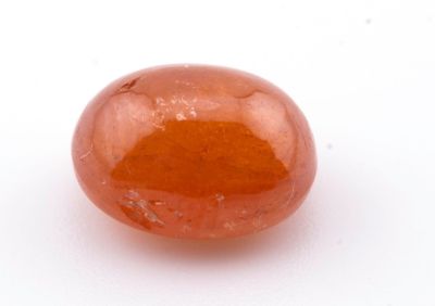 un gros plan d'une pierre rouge sur une surface blanche
