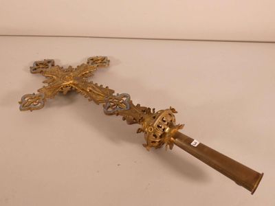 a gold cross on a white surface with a wooden handle