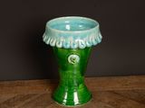 a green vase sitting on a wooden table with a black background