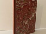 un livre à la couverture rouge posé sur une table blanche