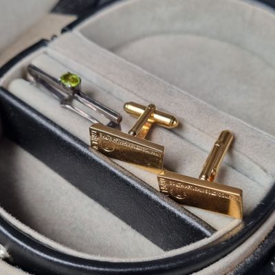 deux boutons de manchette en or dans un étui orné d'une paire de ciseaux