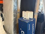 Des cartons contenant des matelas et d'autres meubles sont empilés dans un entrepôt