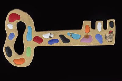 a gold key shaped like a keyhole with colorful stones on it