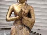 une statue en or représentant une personne assise sur une table