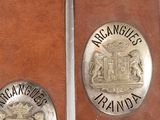 two silver colored medallions on a brown leather case
