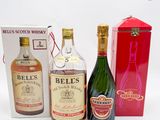 trois bouteilles d'alcool et une boîte de vin posées sur une surface blanche