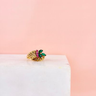 un gros plan d'une bague en or sertie de pierres vertes et roses